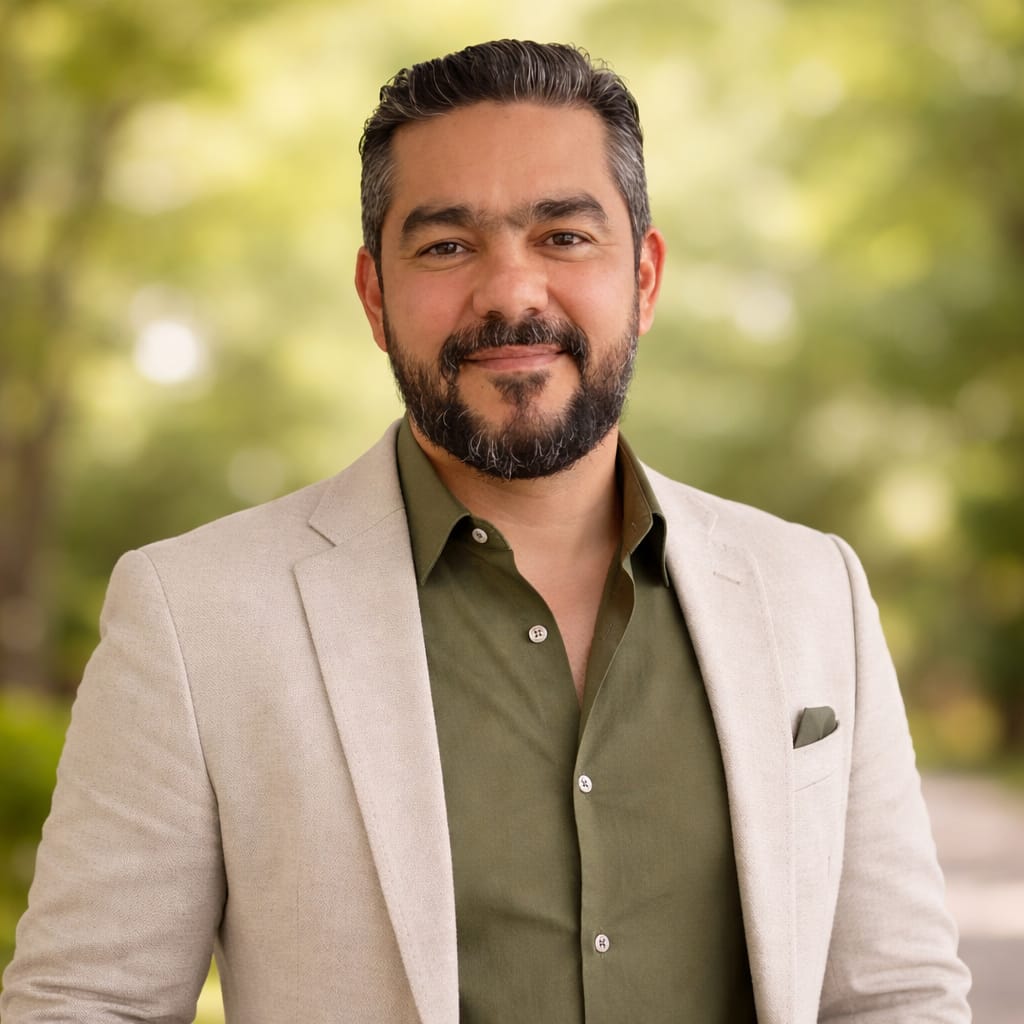 Daniel Vieira, psicólogo, sorrindo em ambiente externo com vegetação ao fundo